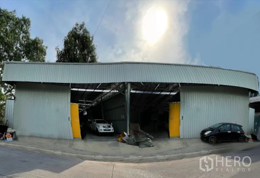 Warehouse for rent in Don Mueang, Bangkok - Street-facing metal-clad warehouse in Don Mueang with high roof, wide yellow doors and drive-in parking.