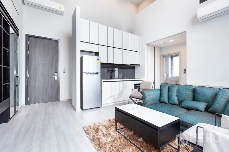 Condominium for rent in Phra Khanong, Bangkok - Entry view showing minimalist kitchen, sofa set and light wood flooring.