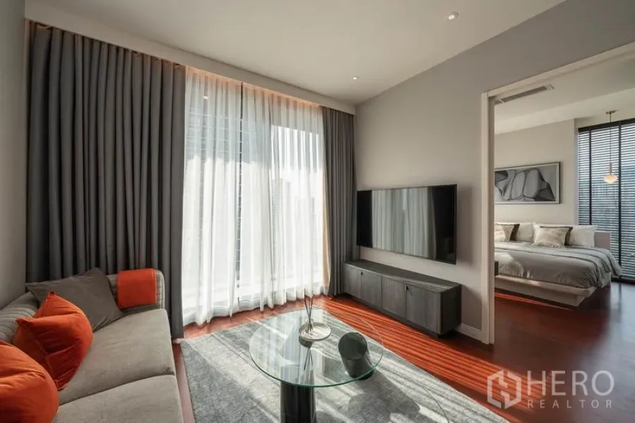 คอนโด ให้เช่าในWatthana, Bangkok - ห้องนั่งเล่น ผ้าม่านสูงจรดเพดาน ทีวีติดผนัง และทางเข้าห้องนอน