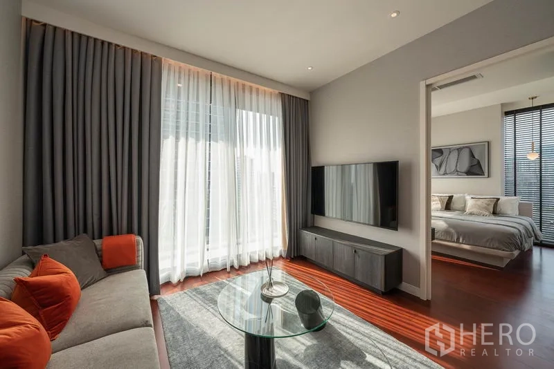 คอนโด ให้เช่าในWatthana, Bangkok - ห้องนั่งเล่น ผ้าม่านสูงจรดเพดาน ทีวีติดผนัง และทางเข้าห้องนอน