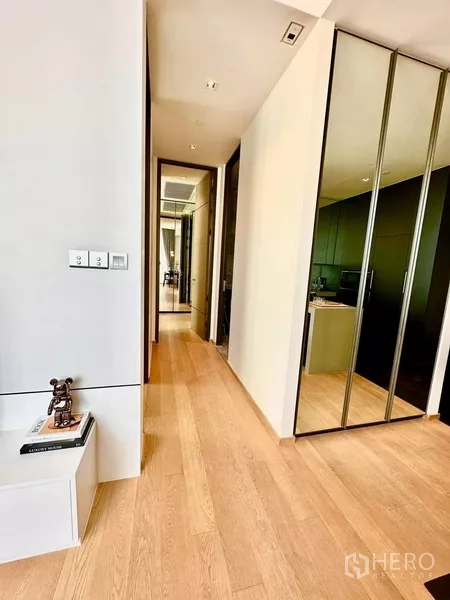 Condominium for rent in Pathum Wan, Bangkok - Entrance corridor with mirrored wardrobes and a compact kitchen in sleek cabinetry.