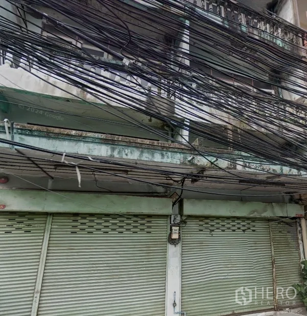 อาคารพาณิชย์ ให้เช่าในPhra Khanong, Bangkok - ด้านหน้าอาคารพาณิชย์สภาพเดิม บานประตูเหล็กม้วน ระเบียง และสายไฟพาดเต็ม