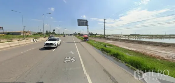 Land for sale in Mueang Samut Sakhon, Samut Sakhon - Dual carriageway on Rama 2 with cars and a small roadside stall next to salt pans.