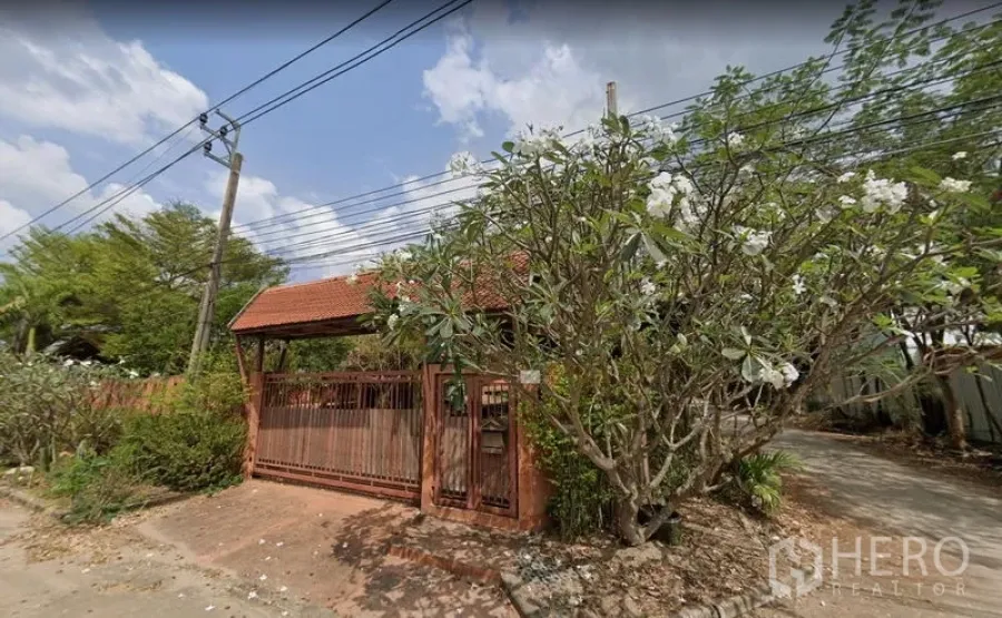 คลังสินค้า ให้เช่าหรือขายในKhlong Sam Wa, Bangkok - ประตูรั้วทางเข้าหลังคากระเบื้องสีแดง รายล้อมด้วยต้นลั่นทม