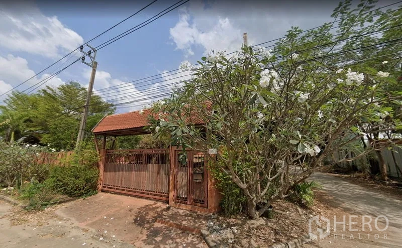 คลังสินค้า ให้เช่าหรือขายในKhlong Sam Wa, Bangkok - ประตูรั้วทางเข้าหลังคากระเบื้องสีแดง รายล้อมด้วยต้นลั่นทม