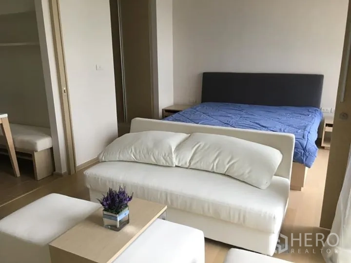 公寓 出租或出售在Watthana, Bangkok - 采光充足的一居室，设有沙发休闲角、双人床与浅色木地板