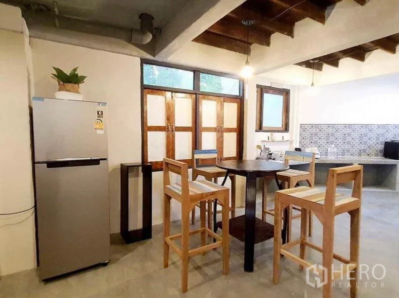 Detached House for rent in Pathum Wan, Bangkok - Eat-in kitchen with round table, tall wooden chairs, stainless fridge and wooden windows