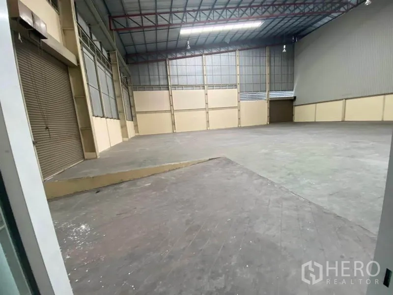 Factory for rent in Bang Phli, Samut Prakan - Warehouse-style interior showing loading ramp, roller shutters, and steel truss roof.