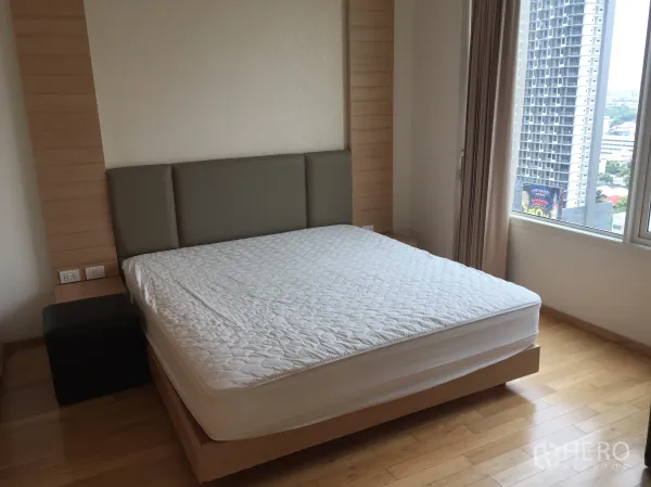 公寓 出租在Sathon, Bangkok - 主卧带软包床头与实木地板，落地窗享城市景观。