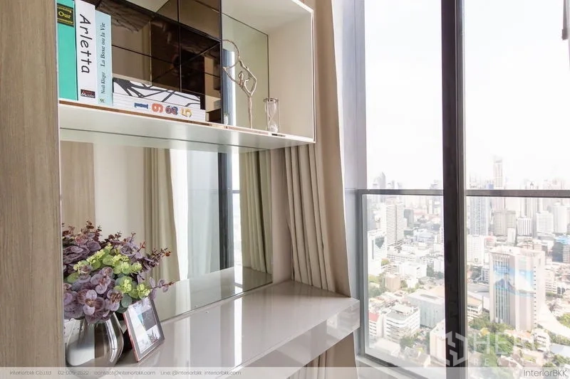Condominium for rent in Pathum Wan, Bangkok - Built-in shelves and glossy console beside a tall window with panoramic city view.