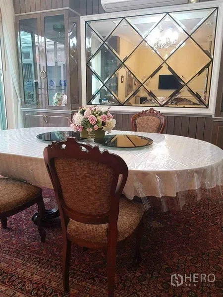 Townhouse for sale in Yan Nawa, Bangkok - Formal dining room featuring an oval table, mirrored wall and glass display cabinets.