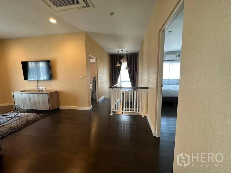 บ้าน ให้เช่าหรือขายในLam Luk Ka, Pathum Thani - ห้องนั่งเล่นชั้นบนพร้อมทีวี พื้นไม้ และราวกันตกเชื่อมห้องนอน