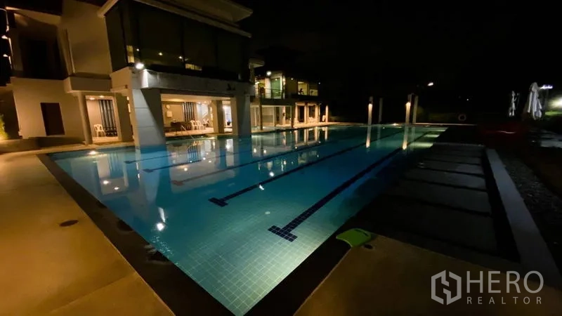 Detached House for rent in Bang Kapi, Bangkok - Night view of illuminated communal swimming pool and clubhouse.