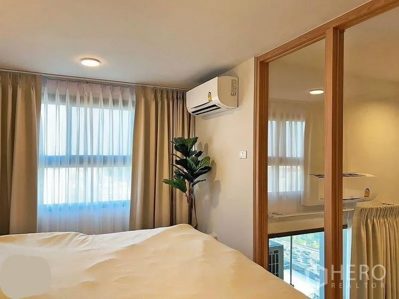 คอนโด ให้เช่าในHuai Khwang, Bangkok - มุมห้องนอนชั้นลอย กั้นกระจกบานเลื่อน หน้าต่างผ้าม่าน แอร์ และต้นไม้ภายใน