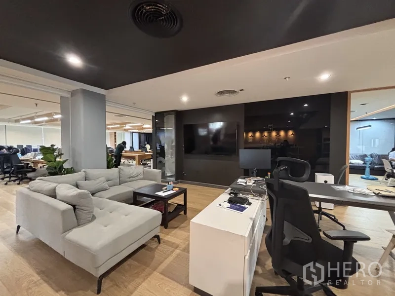 办公室 for rent in Bang Rak, Bangkok - 休闲角落配转角沙发、电视墙与工位，邻近开放办公区。