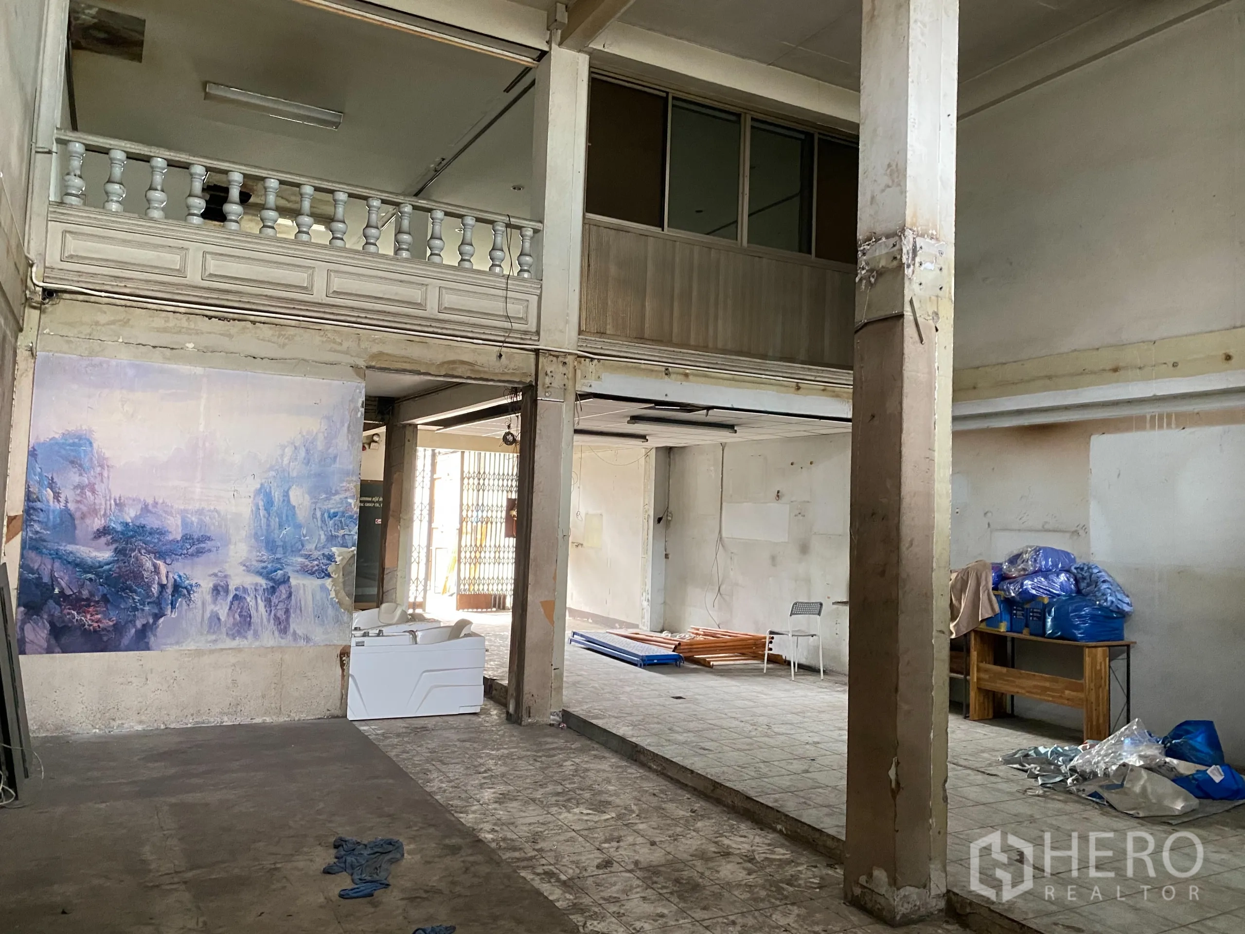 零售空间 出租在Yan Nawa, Bangkok - 零售大厅另一角度，墙面壁画、夹层扶栏与裸露天花。