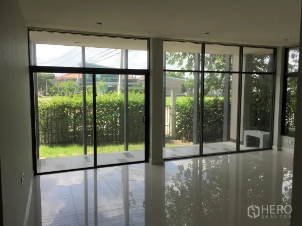 Detached House for rent or sale in Prawet, Bangkok - Floor-to-ceiling sliding doors from the living room opening to a private green garden.