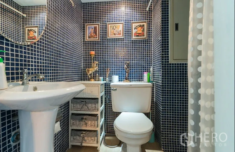 Condominium for rent in Pathum Wan, Bangkok - Bathroom with blue mosaic tiles, pedestal sink and toilet.