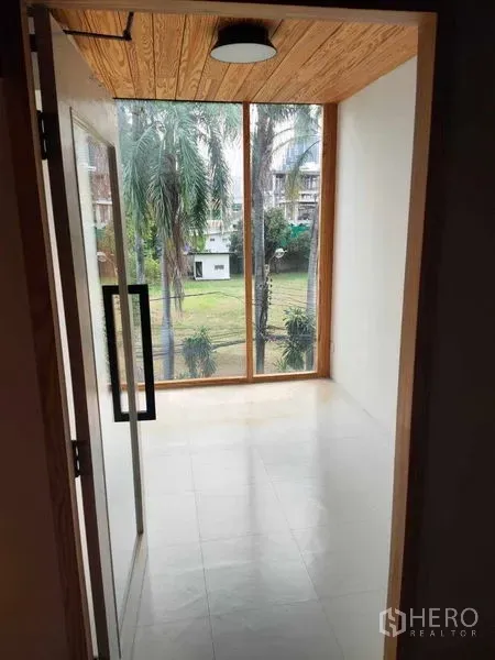 办公空间 出租在Khlong Toei, Bangkok - 小型办公室角落，落地窗面向花园与棕榈树，木质天花与瓷砖地面。