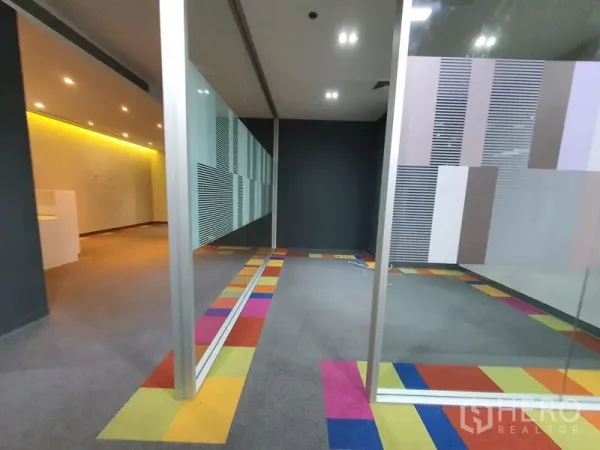 Office Space for rent in Watthana, Bangkok - Glass-partitioned meeting rooms with colorful carpet border and a dark feature wall in a modern office.