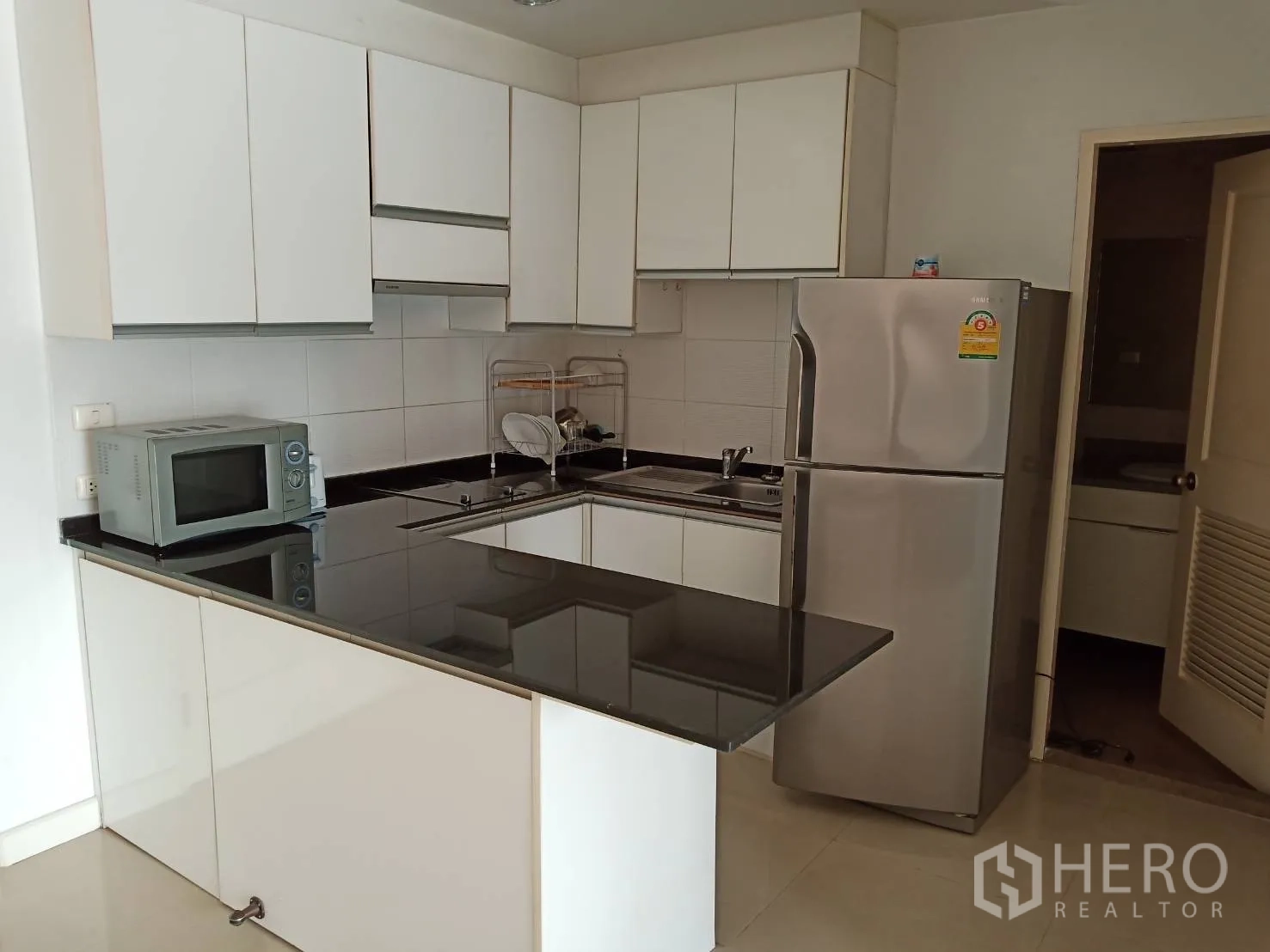 คอนโด ให้เช่าหรือขายในKhlong Toei, Bangkok - ครัวยูเชฟ ตู้สีขาว เคาน์เตอร์หินแกรนิตสีดำ และตู้เย็น