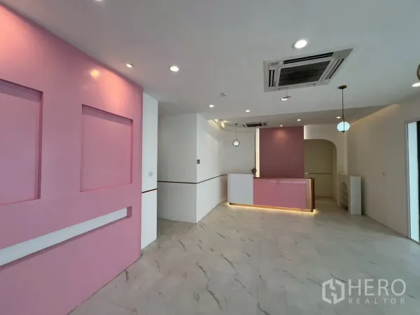 零售空间 出租在Watthana, Bangkok - 开放式零售区，粉色收银台、嵌入式天花空调与射灯。