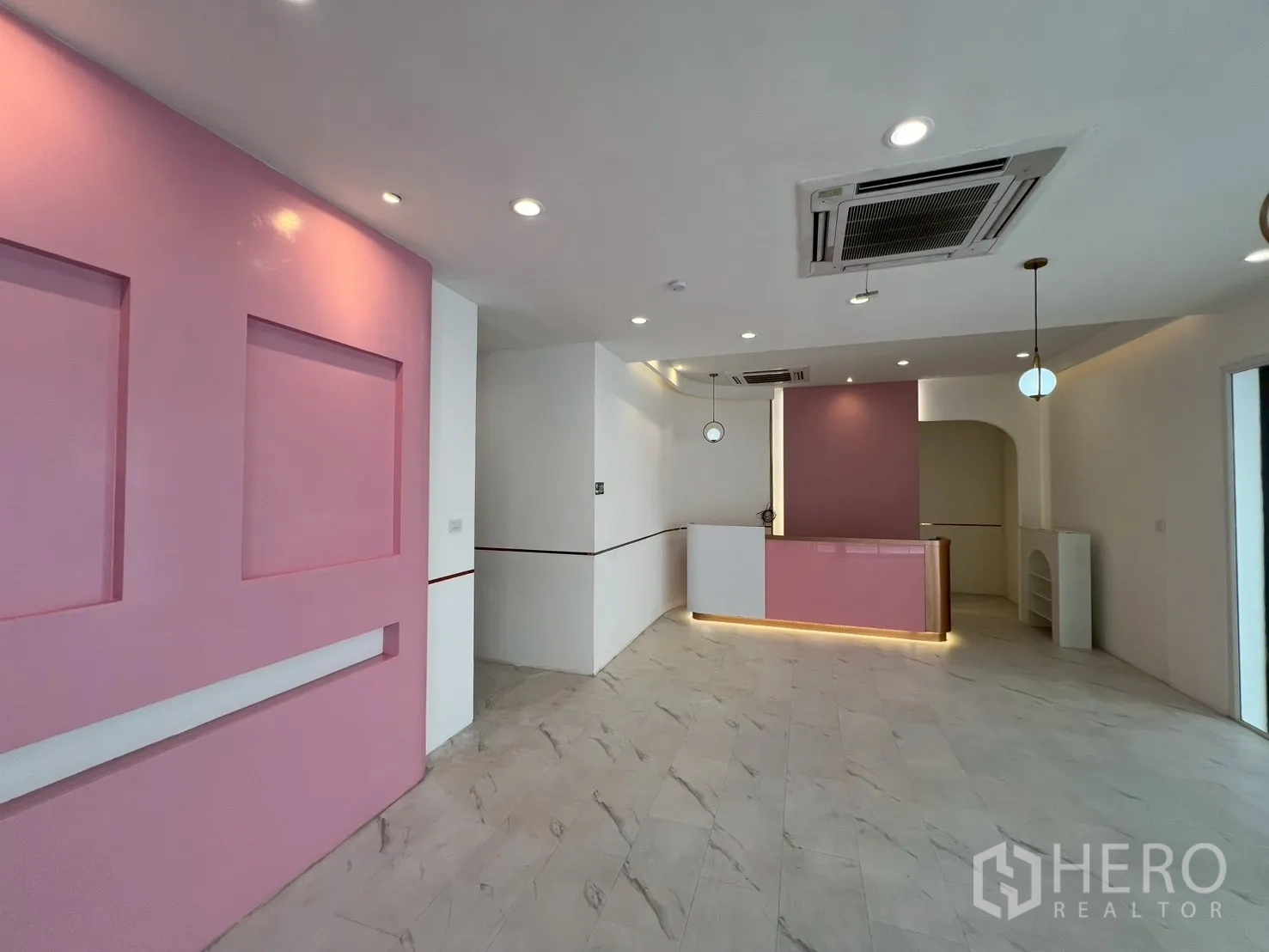 零售空间 出租在Watthana, Bangkok - 开放式零售区，粉色收银台、嵌入式天花空调与射灯。