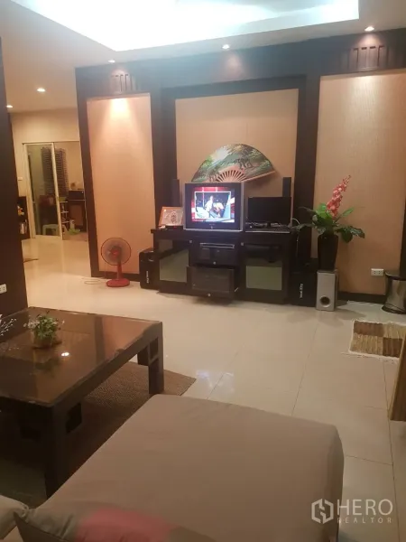 บ้าน ขายในLat Krabang, Bangkok - พื้นที่นั่งเล่นอบอุ่นพร้อมโซฟา โต๊ะกลาง และผนังทีวีบิวท์อิน