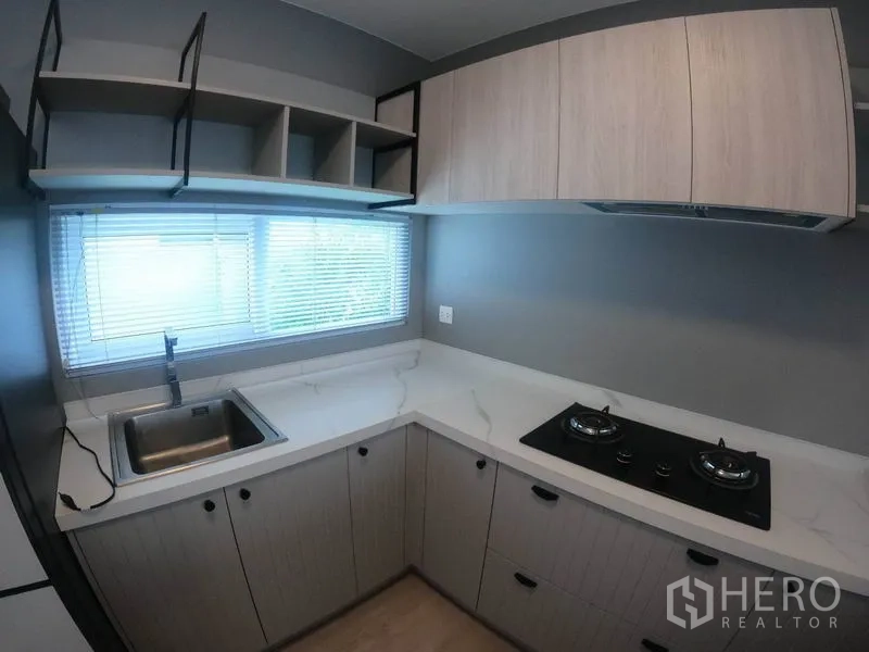 Detached House for rent in Prawet, Bangkok - Compact U-shaped kitchen with window, sink, gas hob and ample cabinets.