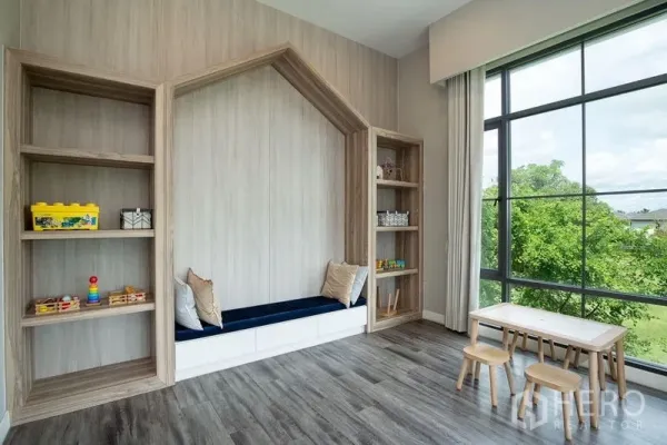 独立式住宅 出租在Bang Phli, Samut Prakan - 家庭活动室，木质嵌入式书架与坐榻，整面落地窗观景。