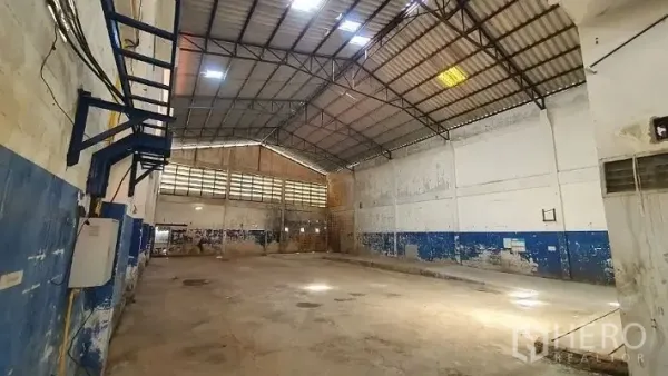 Warehouse for rent in Phra Samut Chedi, Samut Prakan - Wide clear-span hall featuring a steel truss roof with skylights and ventilated block walls over a durable concrete floor.