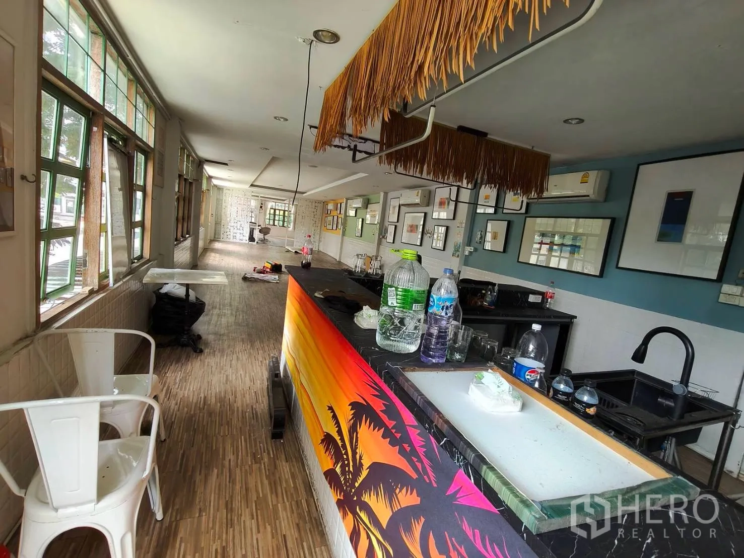 Retail Space for rent in Sathon, Bangkok - Spacious retail interior with a colorful bar counter, wood-look floors, framed artwork, and large windows.