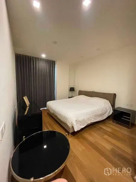 คอนโด ให้เช่าหรือขายในKhlong Toei, Bangkok - ห้องนอนที่สองพร้อมเตียง โต๊ะข้างไฟดาวน์ไลท์ และผ้าม่านสีเข้ม