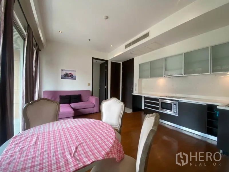 Condominium for rent in Yan Nawa, Bangkok - Open-plan lounge with kitchenette and dining area, hardwood floors and recessed lighting.