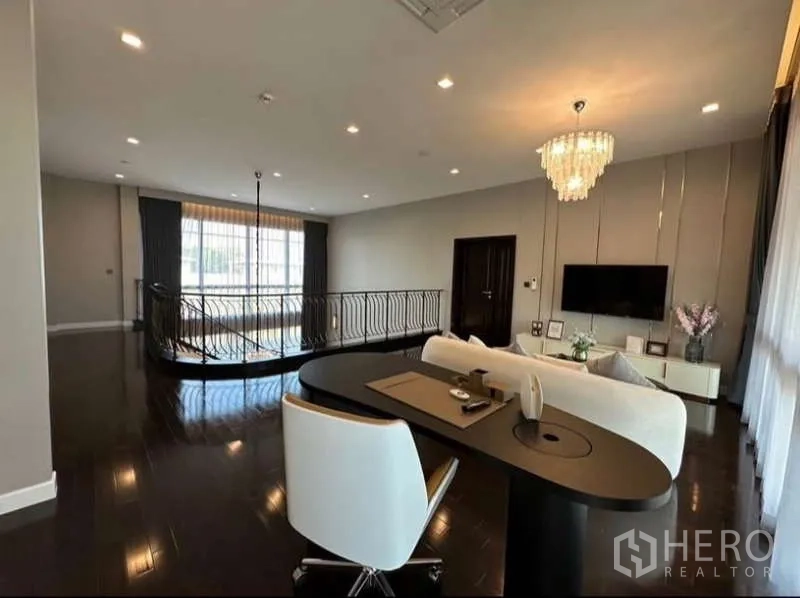 บ้าน ให้เช่าในLat Krabang, Bangkok - ห้องนั่งเล่นชั้นบนพร้อมมุมทำงาน โคมระย้า พื้นไม้เข้ม และราวบันไดโค้ง