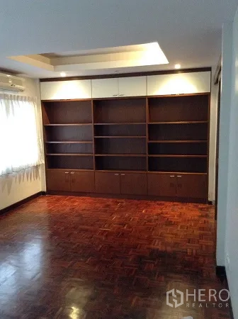 Detached House for rent in Ratchathewi, Bangkok - Spacious room with built-in wall shelves, recessed ceiling lights and polished wood floors.