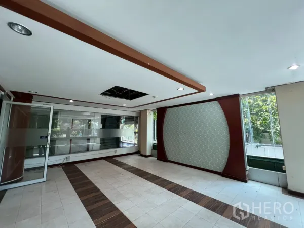 Retail Space for rent - Bright retail interior with tiled floors, wood accents, frosted-glass partition and large street-facing windows in Sathon, Bangkok.