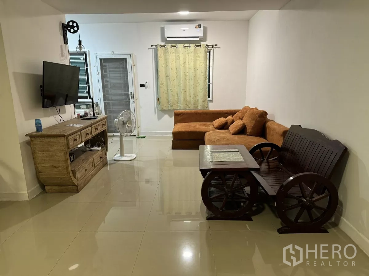 ทาวน์เฮาส์ ให้เช่าในSuan Luang, Bangkok - ห้องนั่งเล่นติดแอร์ โซฟารูปตัวแอล ตู้วางทีวี ม้านั่งไม้ และพื้นกระเบื้องมัน