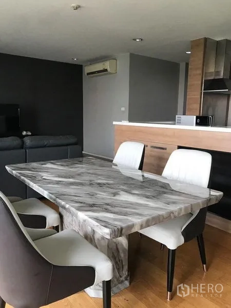 公寓 出租在Watthana, Bangkok - 开放式餐区配大理石餐桌与软包座椅，毗邻现代厨房与客厅。