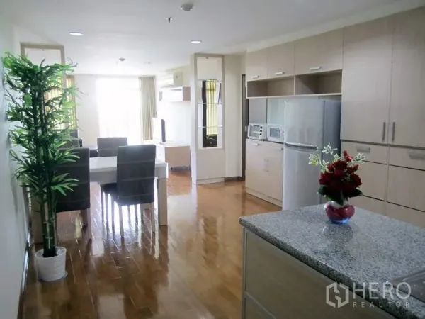 公寓 出租在Bang Rak, Bangkok - 明亮的开放式厨房与餐区，浅木柜体、岛台和抛光木地板。