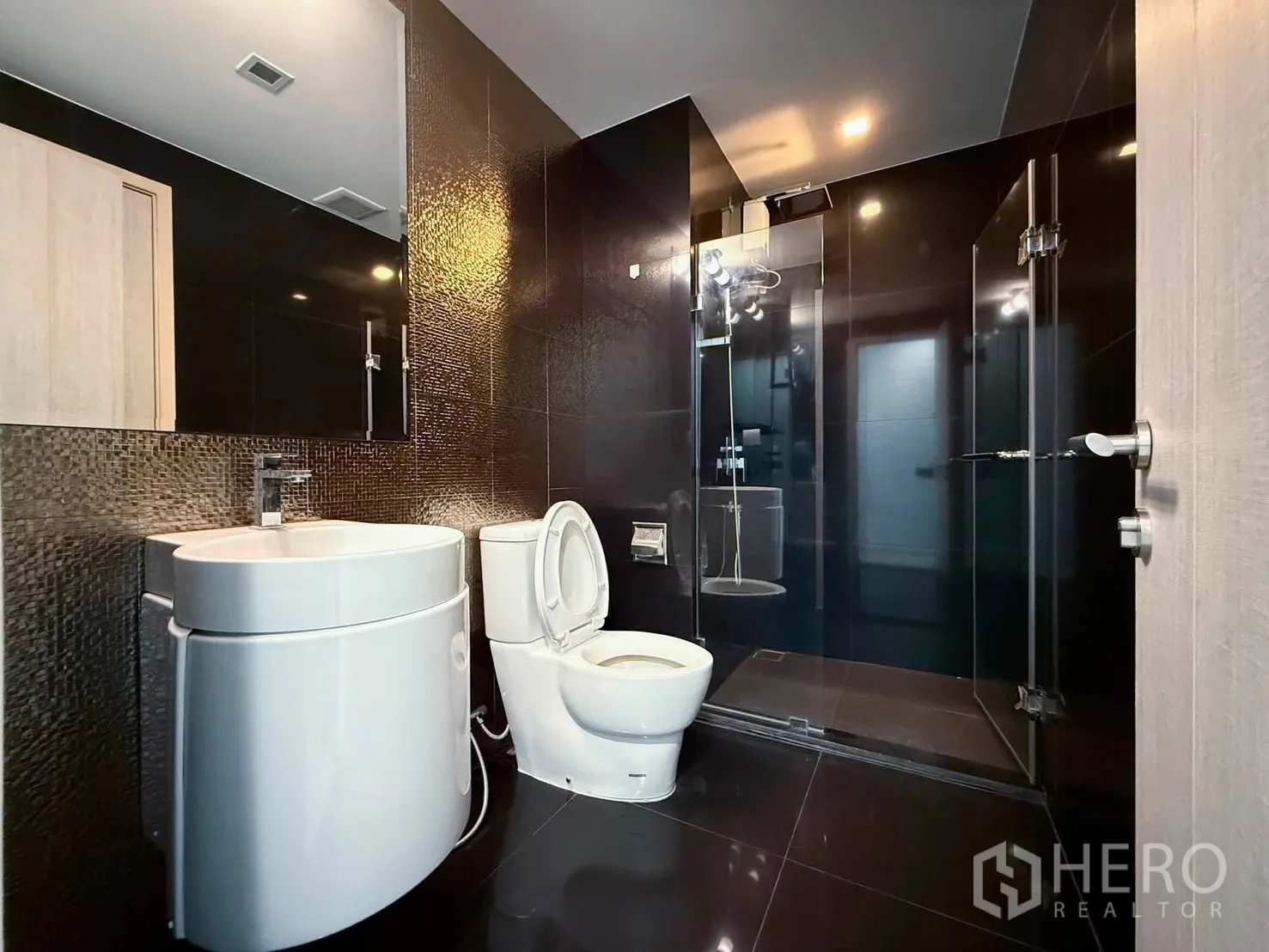 Condominium for rent in Khlong Toei, Bangkok - Contemporary bathroom with glass shower enclosure and sleek vanity.