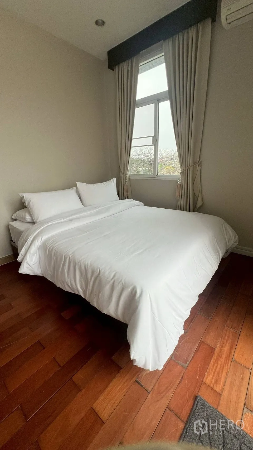 Detached House for rent in Lat Krabang, Bangkok - Cozy bedroom with white bedding, window and wooden floors.