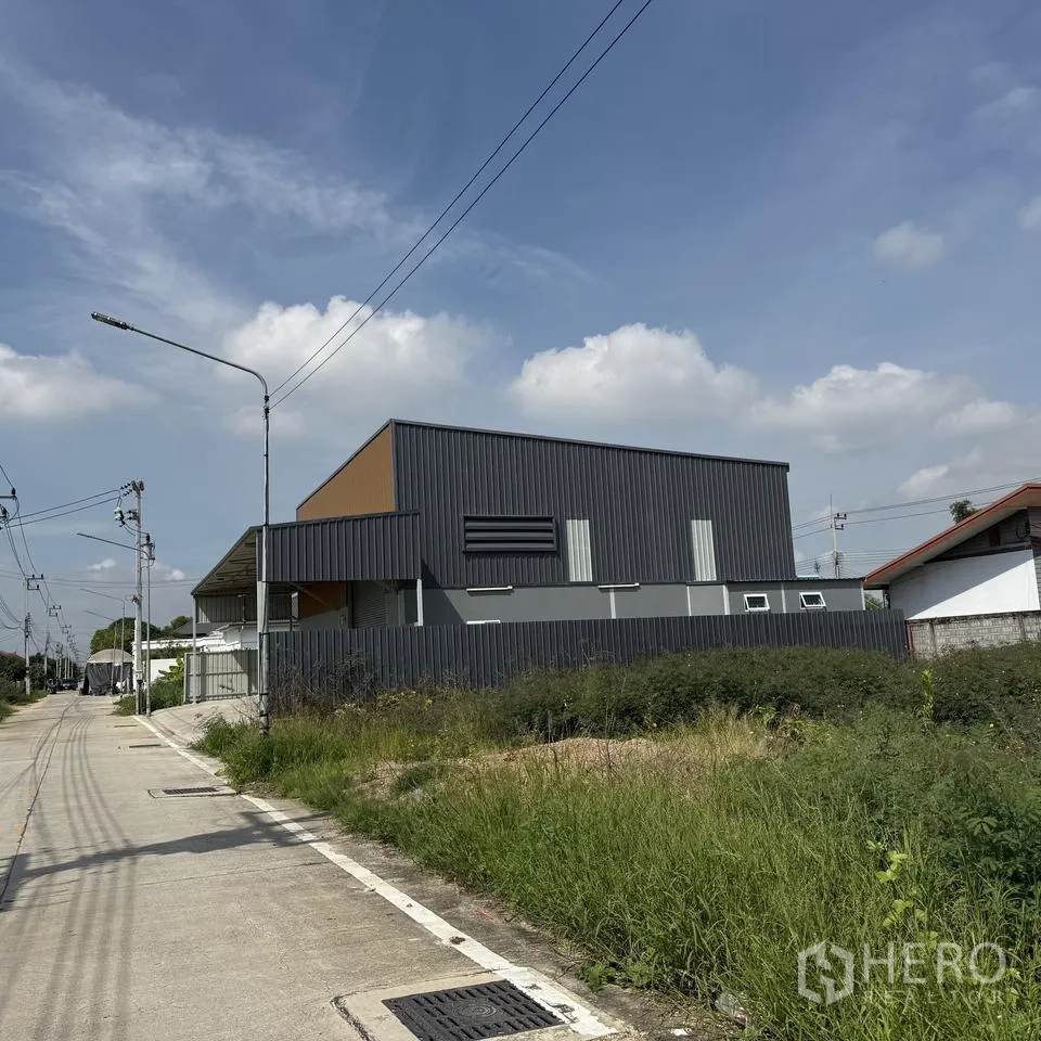 仓库 for rent or sale in Khlong Luang, Pathum Thani - 仓库侧立面临本地道路，周边设围栏。