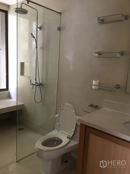 คอนโด ให้เช่าในKhlong Toei, Bangkok - ห้องน้ำสมัยใหม่พร้อมตู้กระจกอาบน้ำแบบเรนชาวเวอร์ ชั้นวางผนัง และเคาน์เตอร์ไม้โทนอ่อน