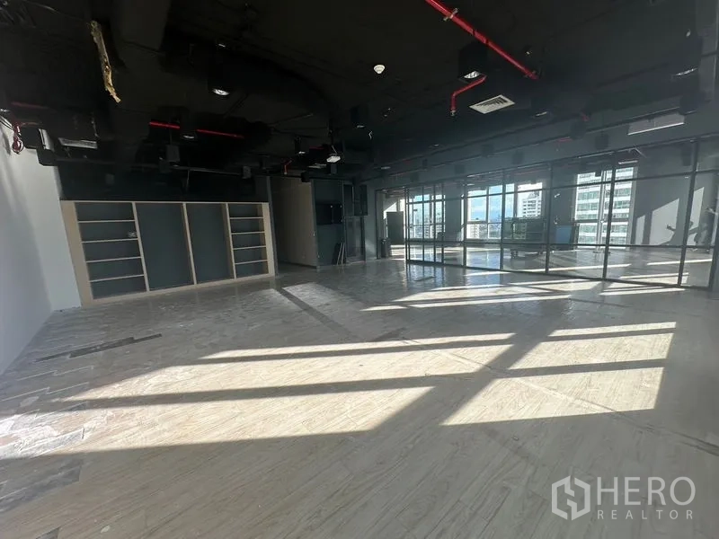 Office Space for rent in Bang Rak, Bangkok - Spacious corner zone with built‑in shelving and a full-height glass wall.