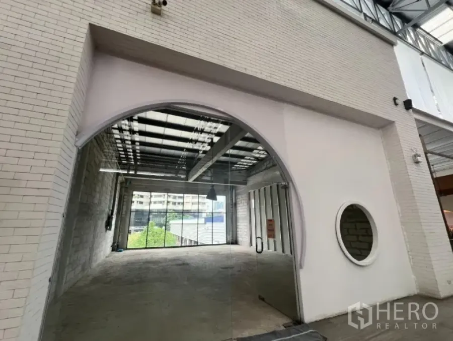 พื้นที่ขายปลีก ให้เช่า - พื้นที่ค้าปลีกชั้น 2 ทางเข้าโค้งกระจก ผนังอิฐสีขาวและหน้าต่างทรงกลม ในเขตคลองเตย