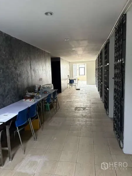 Office Space for rent in Khlong Toei, Bangkok - Long corridor workspace with tables and metal security grilles.