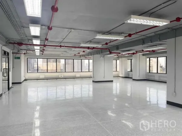 Office Space for rent in Bang Rak, Bangkok - Open workspace near a glass entry door, ducted ceiling with sprinklers, and multiple panoramic windows.