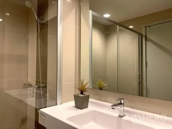 公寓 出租或出售在Phra Khanong, Bangkok - 现代浴室，超大镜面、白色台盆与玻璃淋浴间。