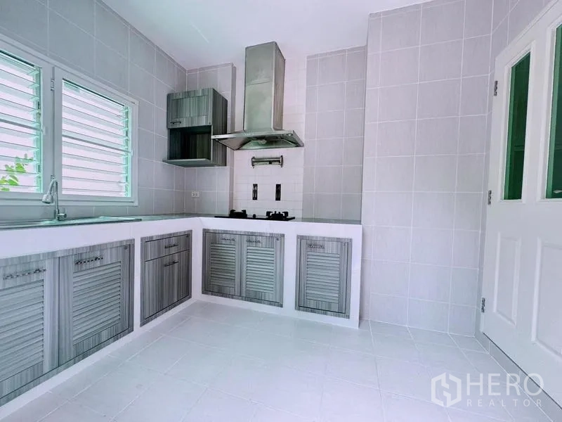 Detached House for rent in Prawet, Bangkok - Separate Thai kitchen with L-shaped cabinets, range hood, and windows.